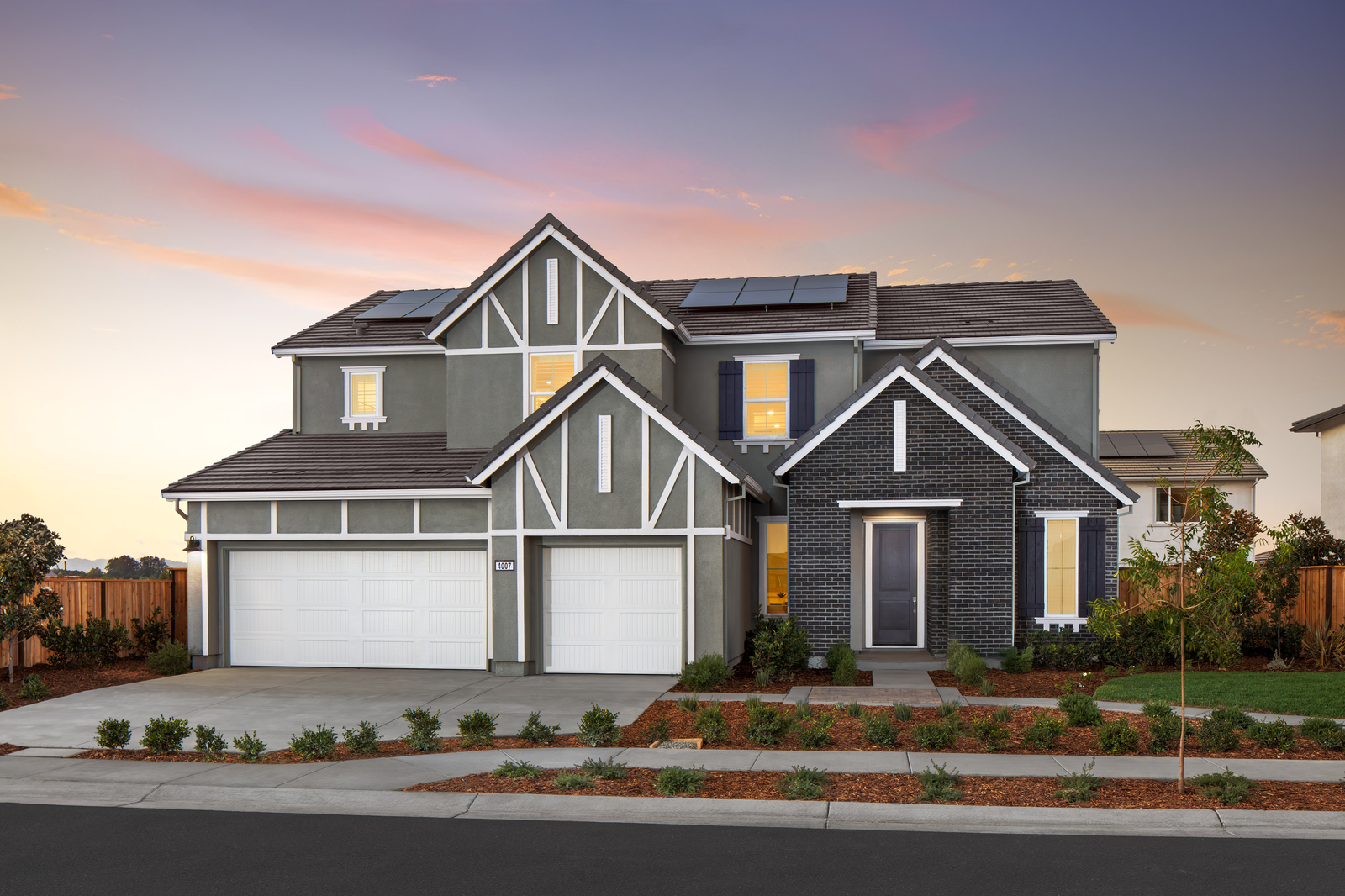 front exterior of two-story gray & white home with three-car garage and solar panels on roof