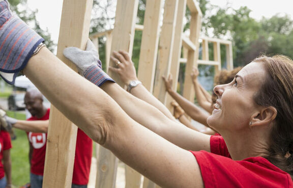 Volunteers putting up a wall of a house