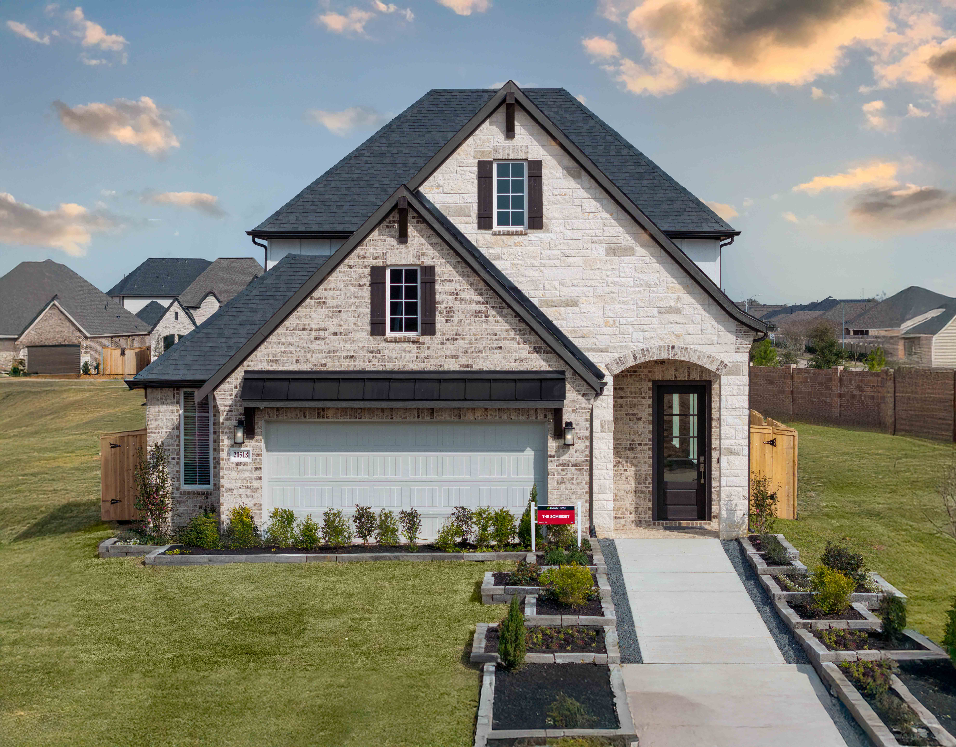 exterior tan brick home with white garage door