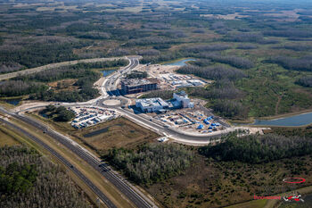 Aerial drone image shows construction in the midst of wilderness and undeveloped land.