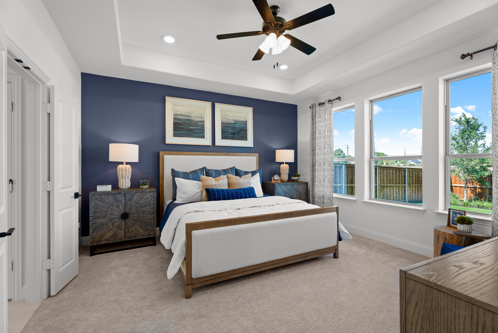 large primary bedroom blue accent wall and windows