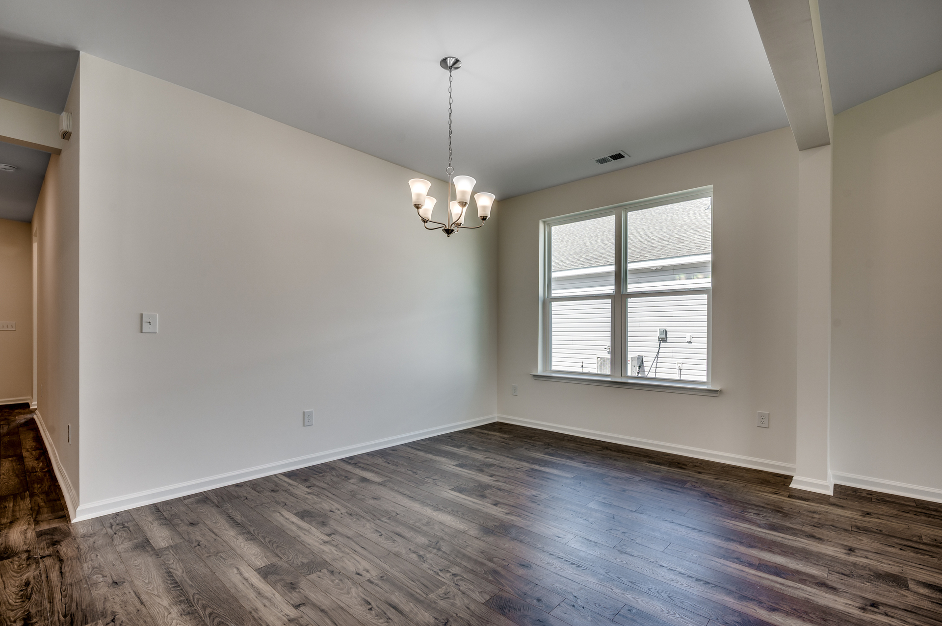 spacious room with large chandelier and hardwood flooring throughout