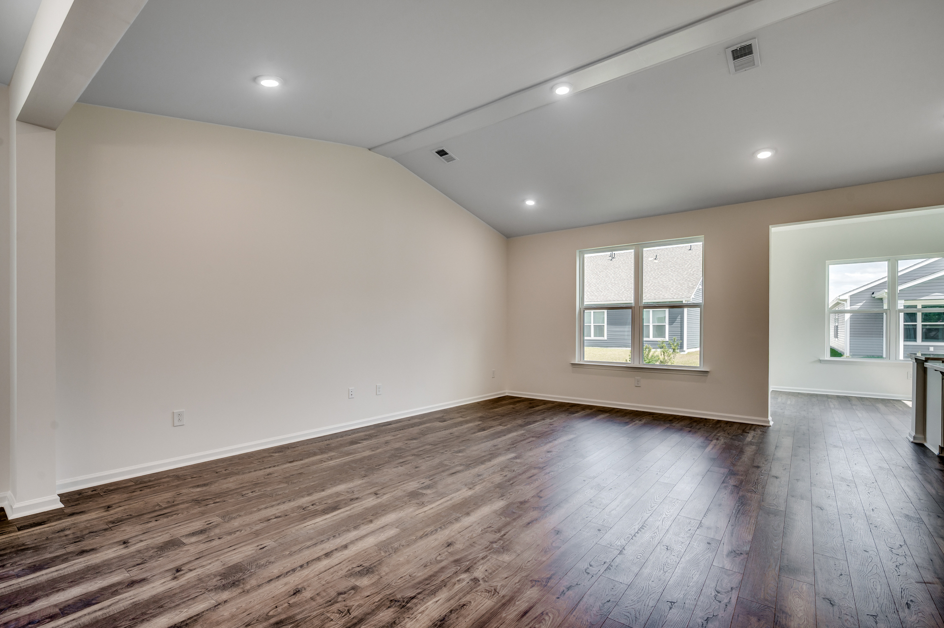 high ceilings with puck lighting, hardwood flooring and tan walls