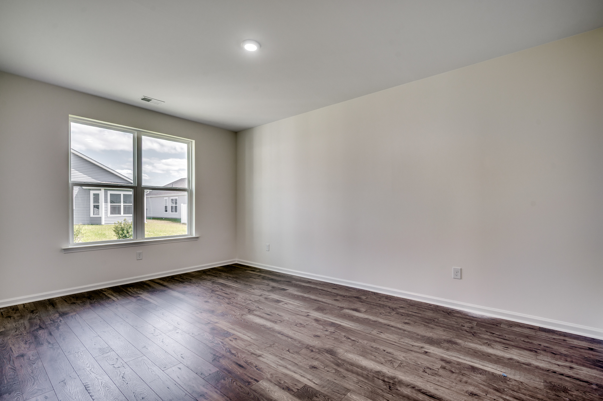 spacious room with high ceiling, window for natural light and hardwood floors
