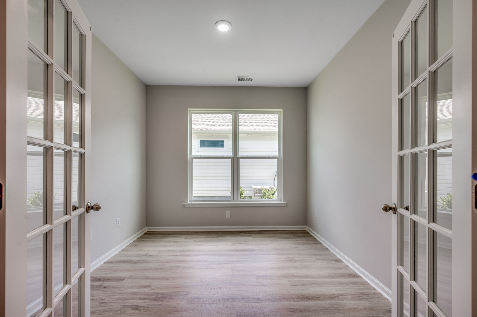 bright room with large windows, glass french doors and hardwood flooring 
