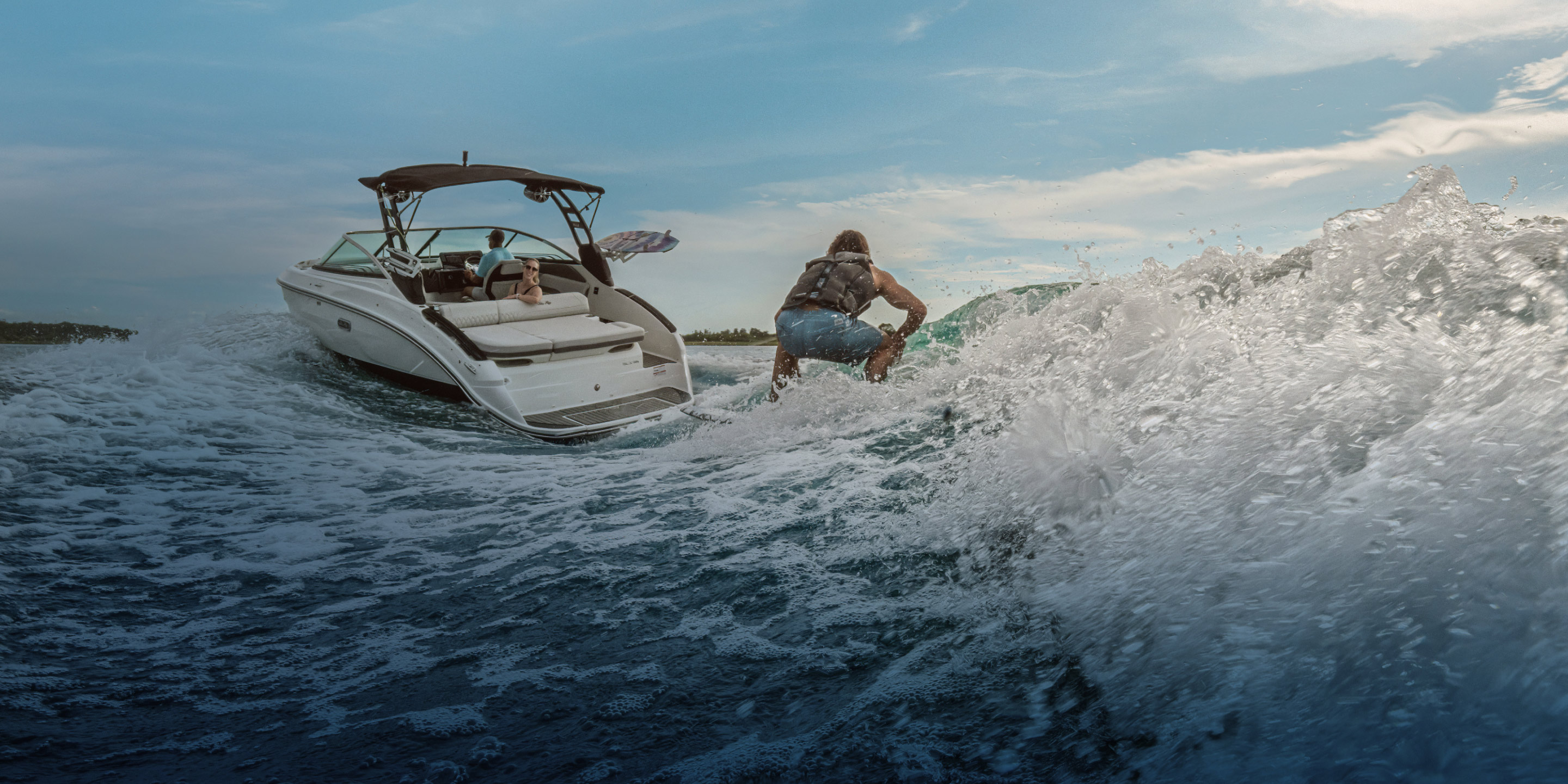 Woman looks back at wake surfer being towed by a powerboat fitted with the Lenco SD Pro System