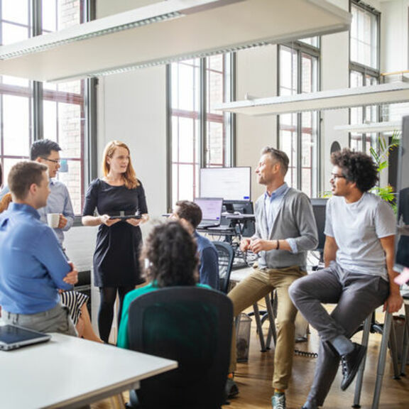 Group of professionals talking in a high-ceiling conference room