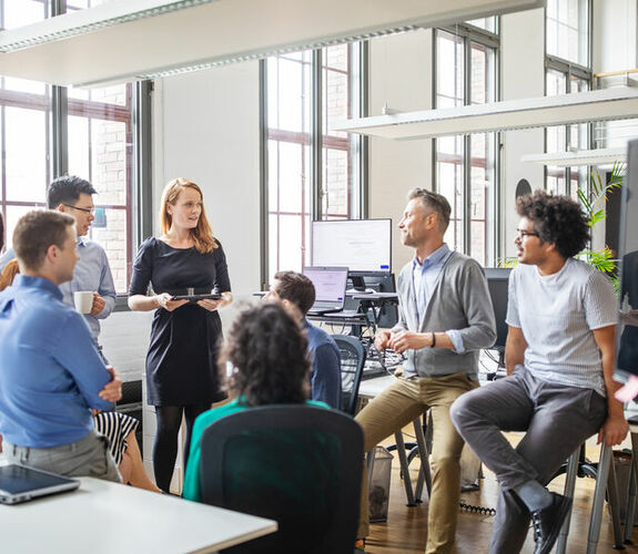 Group of professionals talking in a high-ceiling conference room