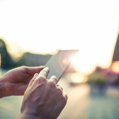 Person holding a mobile device while standing outside
