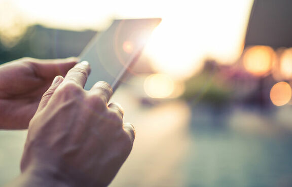 Person holding a mobile device while standing outside