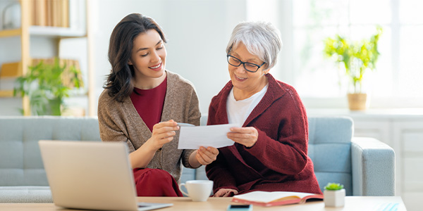 A younger woman and an older woman look at a document together.