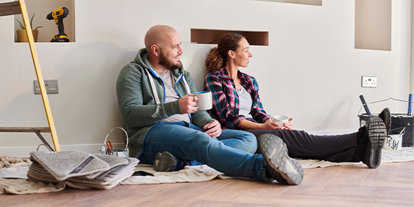 A man and woman sitting on the floor relaxing during a home renovation.