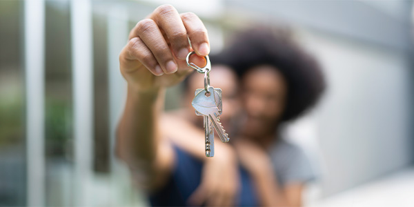 A couple embracing hold up the keys to their new home.