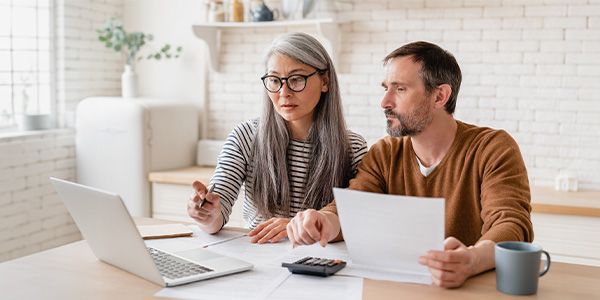 Woman and man looking at documents and laptop computer