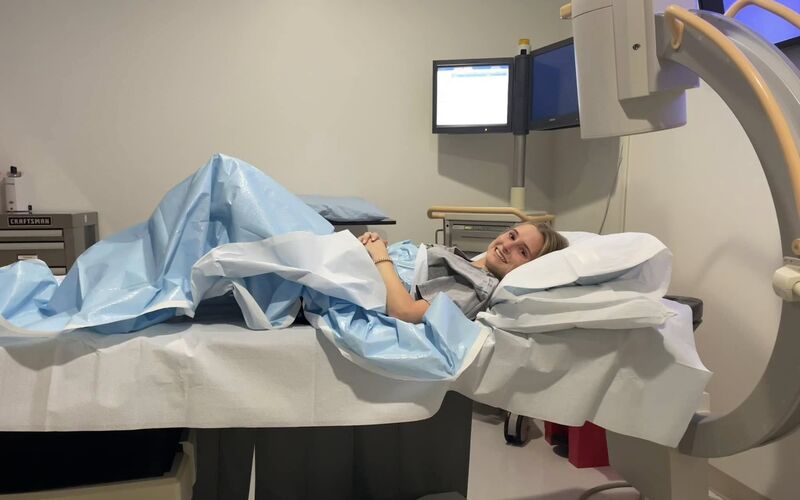 Anna Phelan lying in a hospital bed, smiling at the camera