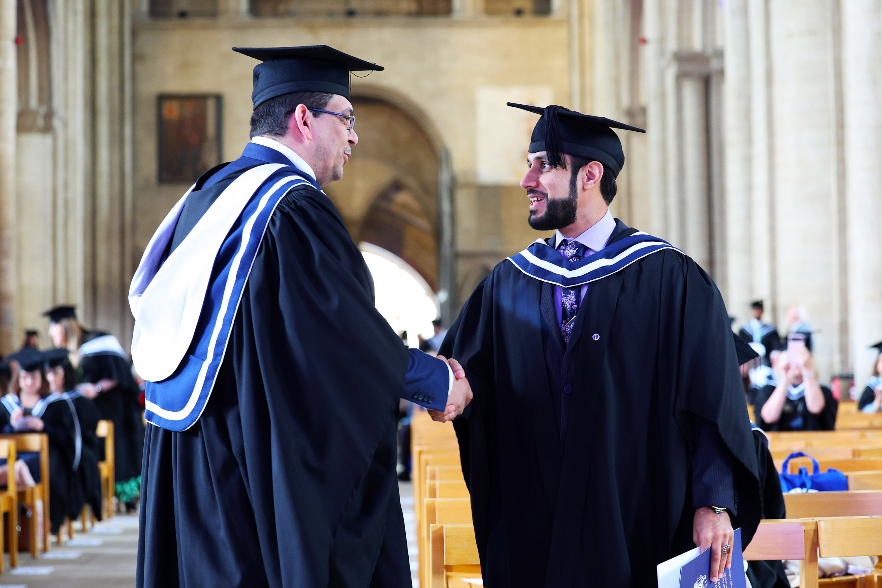 Two graduates shaking hands in venue