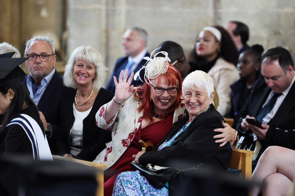 Two women smiling and embracing, with one waving