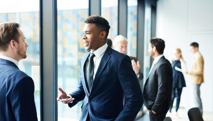 Two intercultural delegates and their colleagues on background discussing