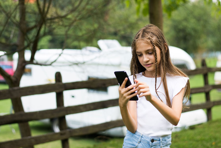 Deklica na počitnicah uporablja telefon brez ozira na varnost na spletu