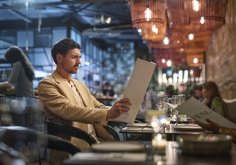 Man in a beige suit has trouble reading restaurant menu