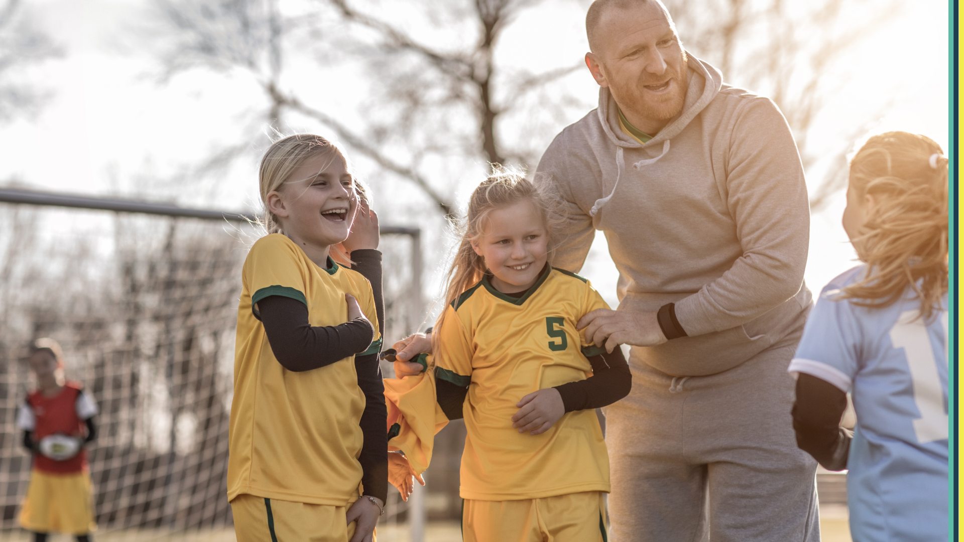 Two little girls smiling and laughing outside on a soccer field in uniform 