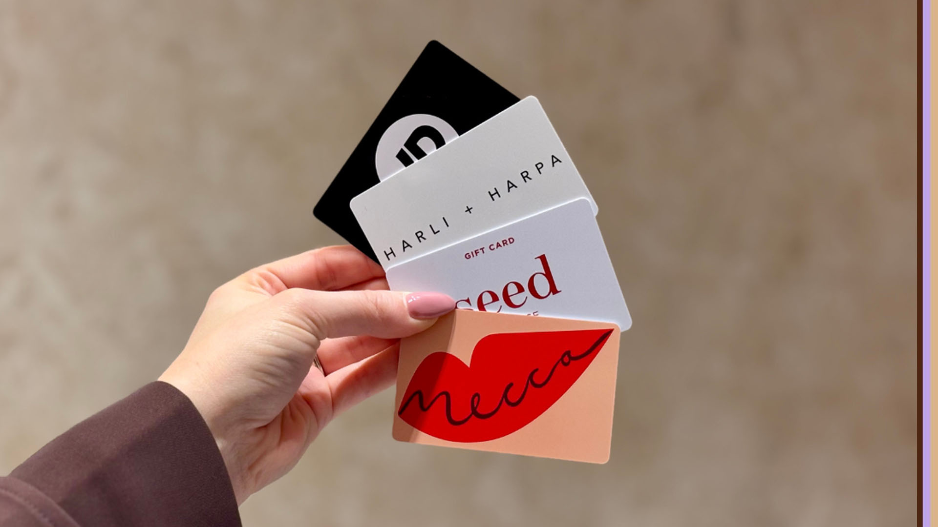 A woman hand holding Mecca, Seed Heritage, Harli + Harpa, and JD Sports Gift Cards