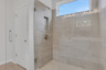 primary bathroom with large walk-in shower and light tile