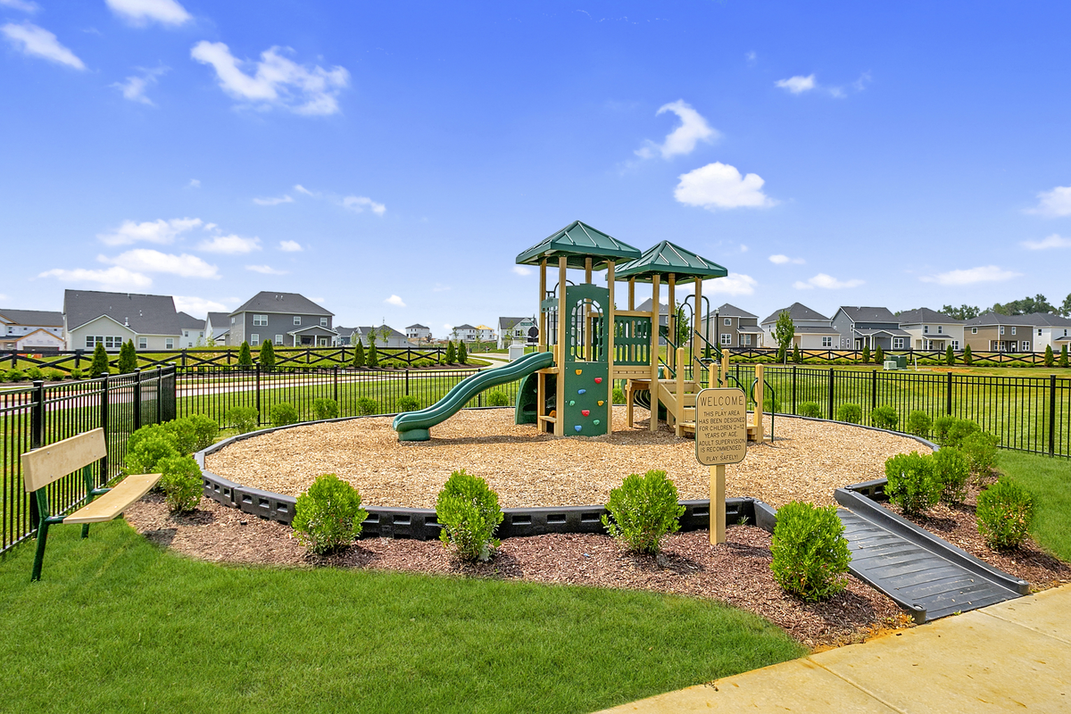 green playground with landscaping and a bench