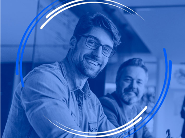 A smiling man wearing glasses and a denim shirt looks at the camera, with a second, smiling man blurred in the background, all framed by blue and white concentric rings overlayed on a dark blue filter.
