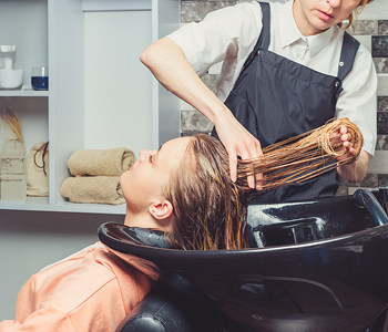 Frizerka med pripravo stranke na barvanje las v frizerskem salonu.