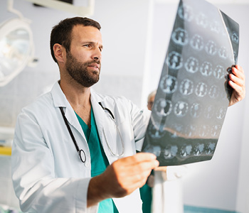 Mlad zdravnik si ogleduje posnetek možganov. Simbolna fotografija za preučevanje alzheimerjeve bolezni.