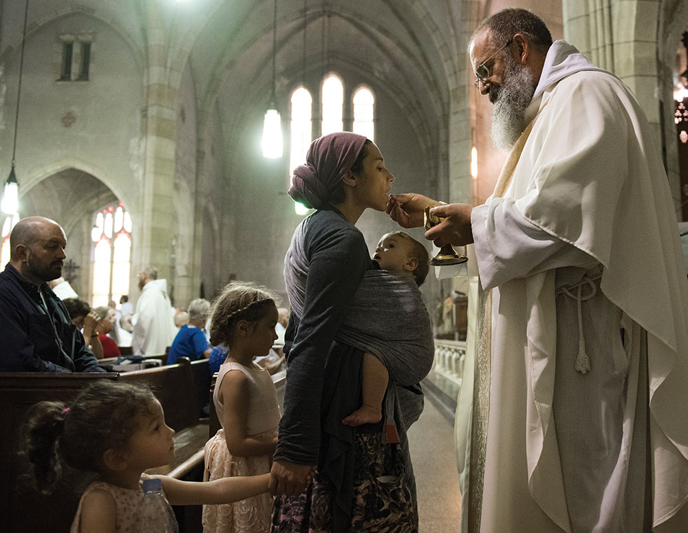 A young mother with her children receives holy Communion