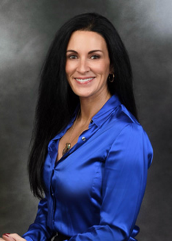 Headshot of Andrea Mackey, who smiles while wearing a cobalt blue blouse