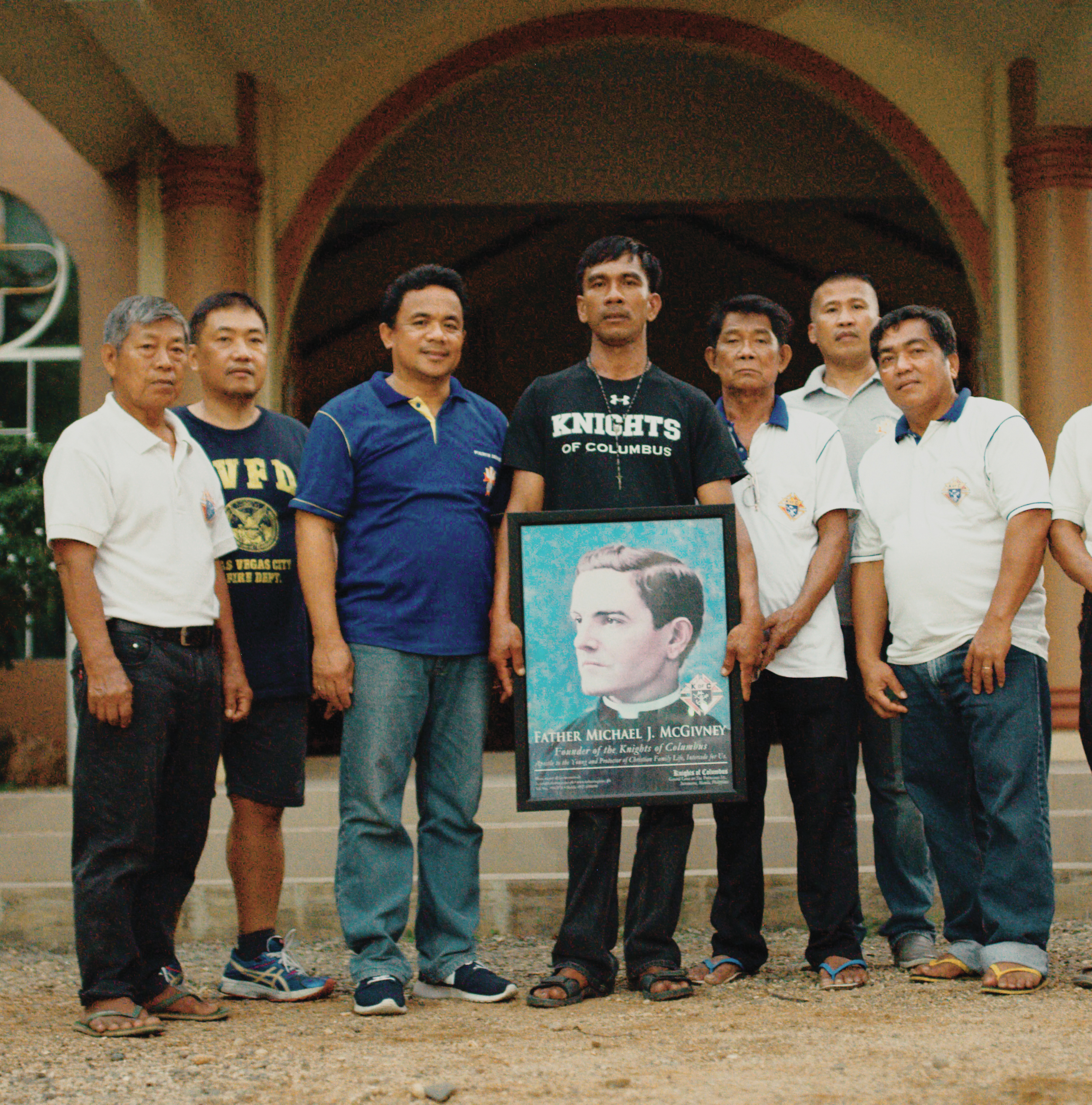 Devotees to Father McGivney posing for photo holding his portrait.