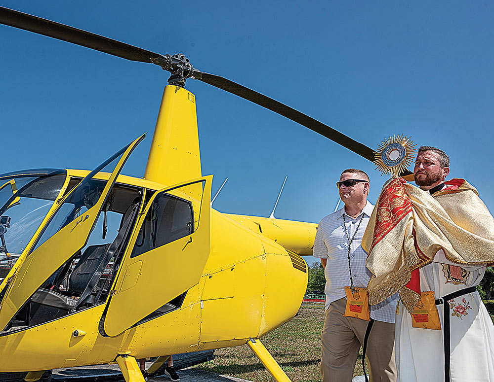 Father Richard Pagano raises the Eucharist in benediction before boarding a helicopter 