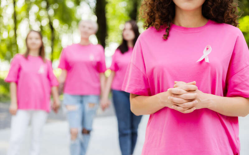 Four women wearing pink shirts with pink breast cancer awareness ribbons