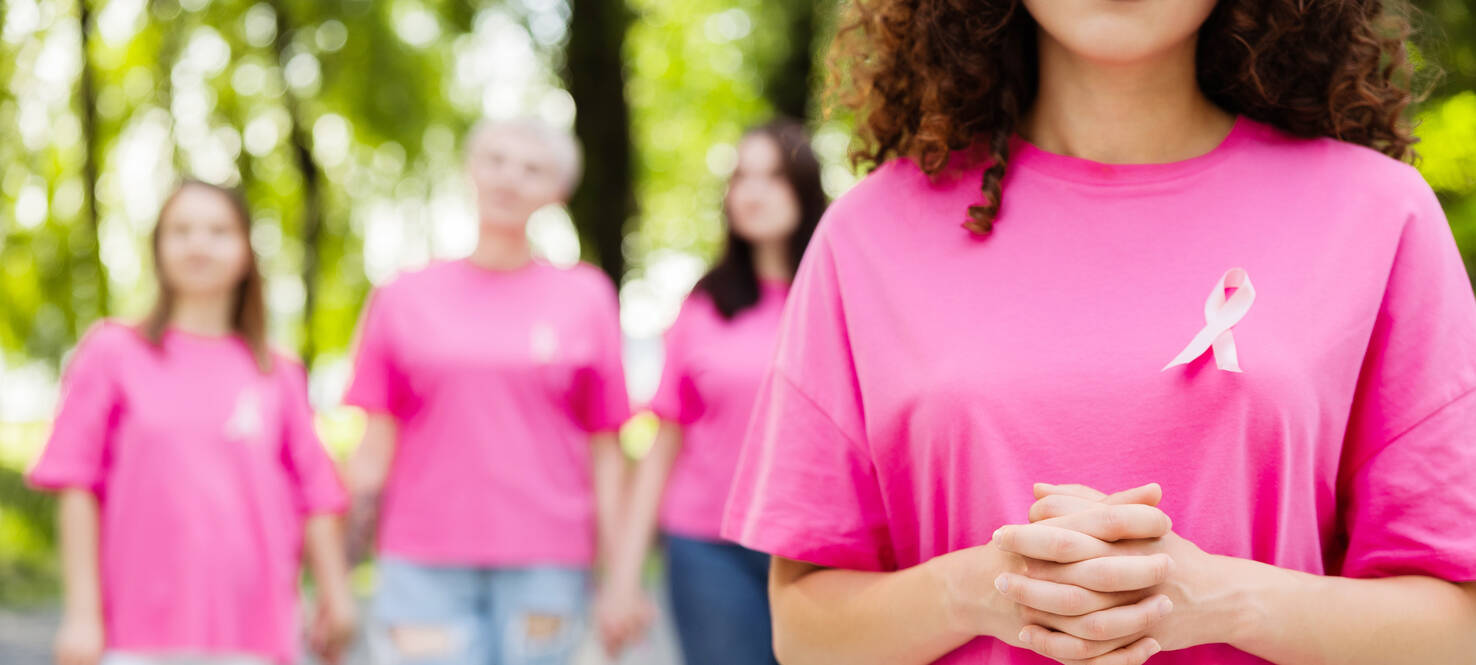 Four women wearing pink shirts with pink breast cancer awareness ribbons