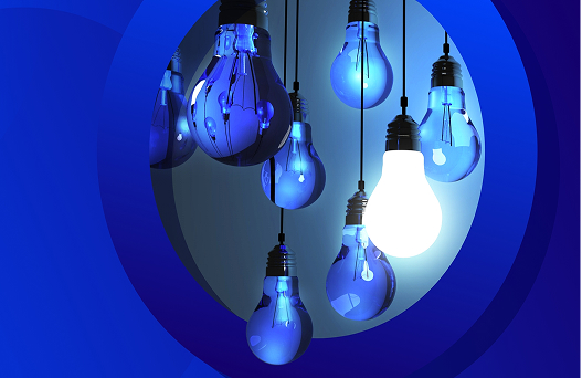 An illustration showing several light bulbs hanging down, mostly glowing a cool blue, with one bulb on the right side brightly lit up in white. The background consists of concentric blue circles and shades of dark blue, suggesting the concept of a single brilliant idea standing out from others.