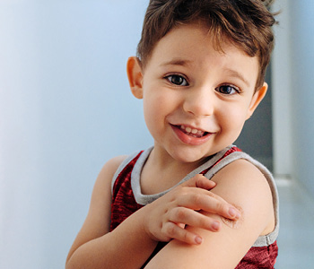 Deček po cepljenju junaško kaže obliž, ki prekriva mesto vboda.