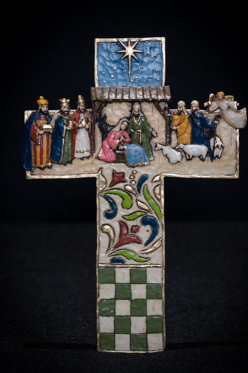 Nativity scene on a cross, with the Holy Family and donkey beneath the stable, and 3 Magi, 2 shepherds, an angel, and 3 sheep on the stable sides. 