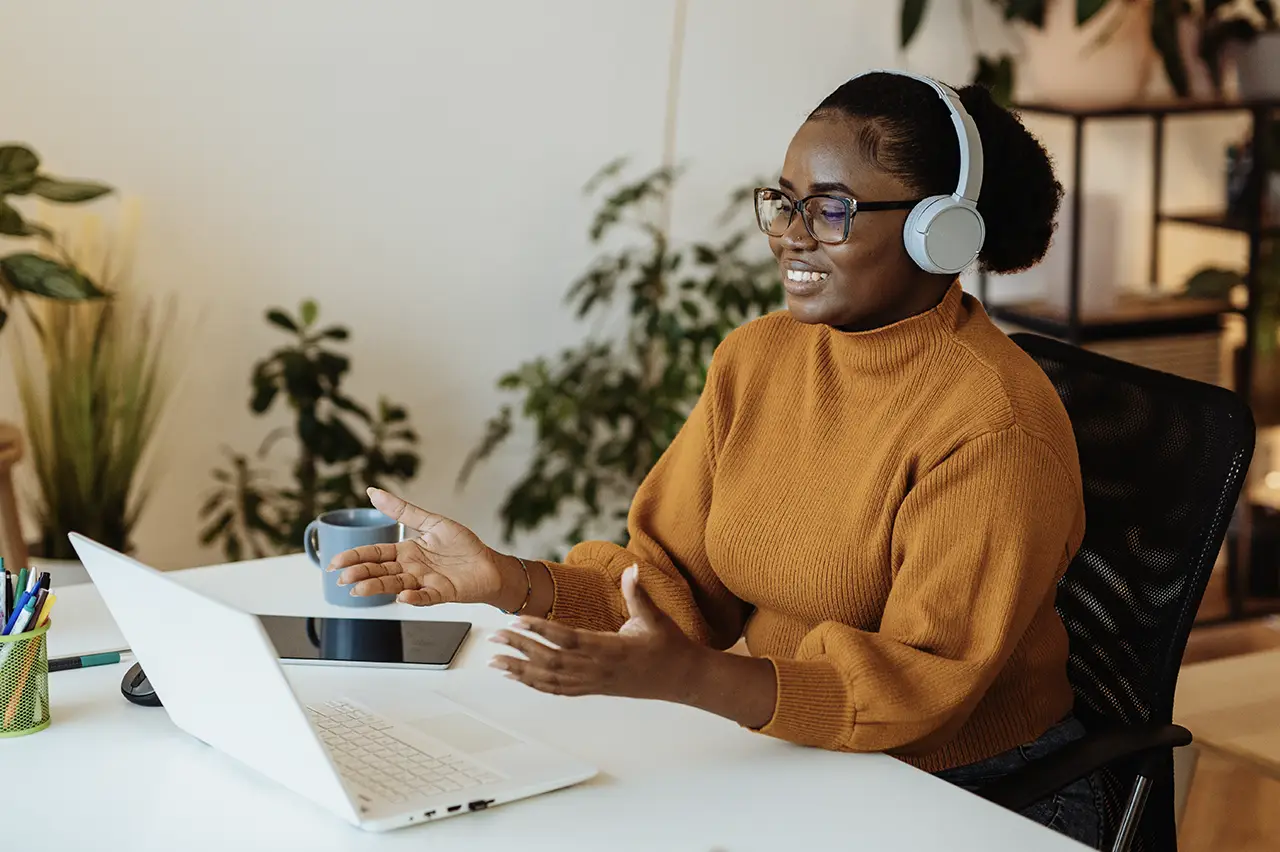 a woman wearing headphones is sitting with her laptop on the desk