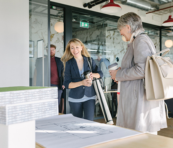 Sodelavci se zbirajo v arhitekturnem biroju, zadovoljni, ker imajo kolektivno zavarovanje.