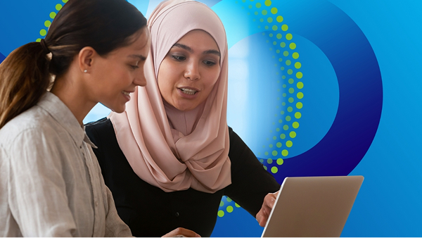 Two women are working together, looking at a laptop screen. One woman is wearing a light pink hijab. The image is overlaid on a background of blue circles and a dotted yellow-green circular arc.