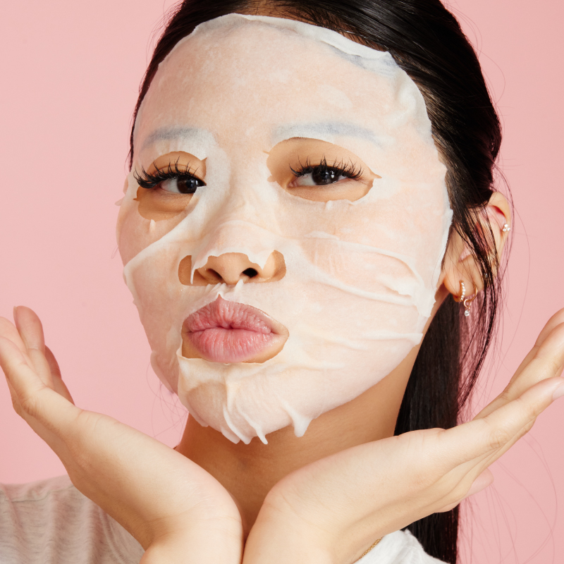 Girl with a white face mask holding her hands to her face and pouting
