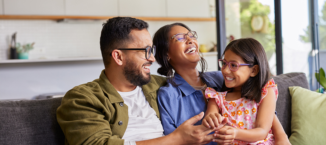 An Indian family sits laughing together on a couch