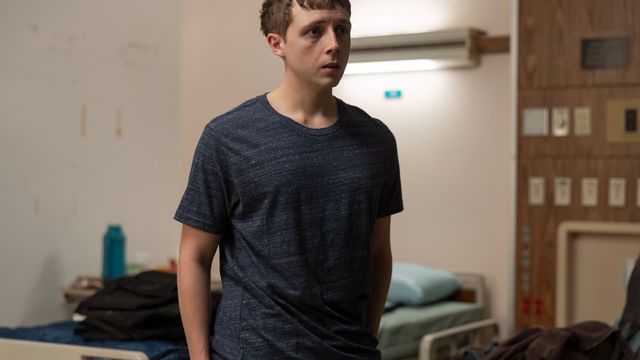 Dennis Whitaker stands in a hospital room near a bed, looking anxious