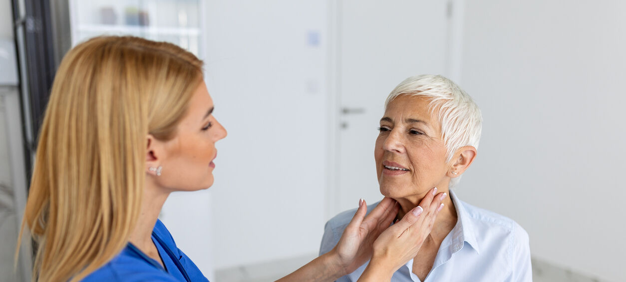 A female health professional exams another woman's neck during an exam.