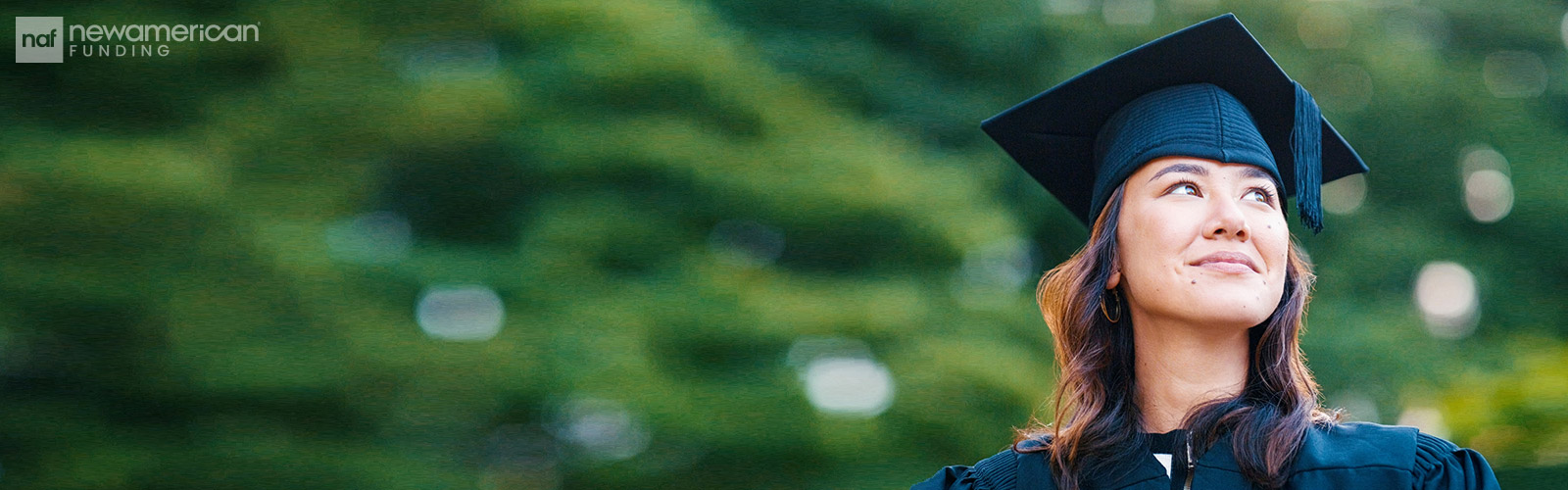 An Asian woman wearing a cap and gown smiles hopefully