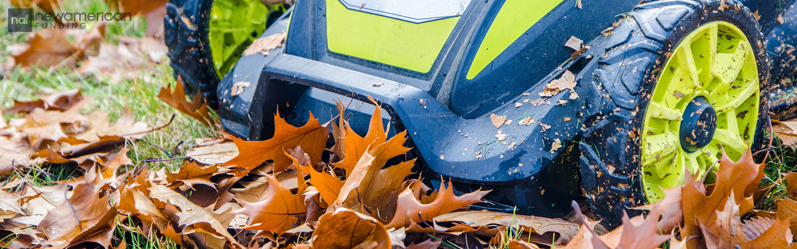 A lawn mower rolls over dried fall leaves on the ground