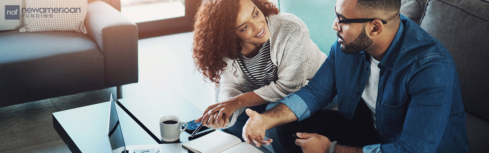 A Black couple talks while looking at a laptop and paperwork